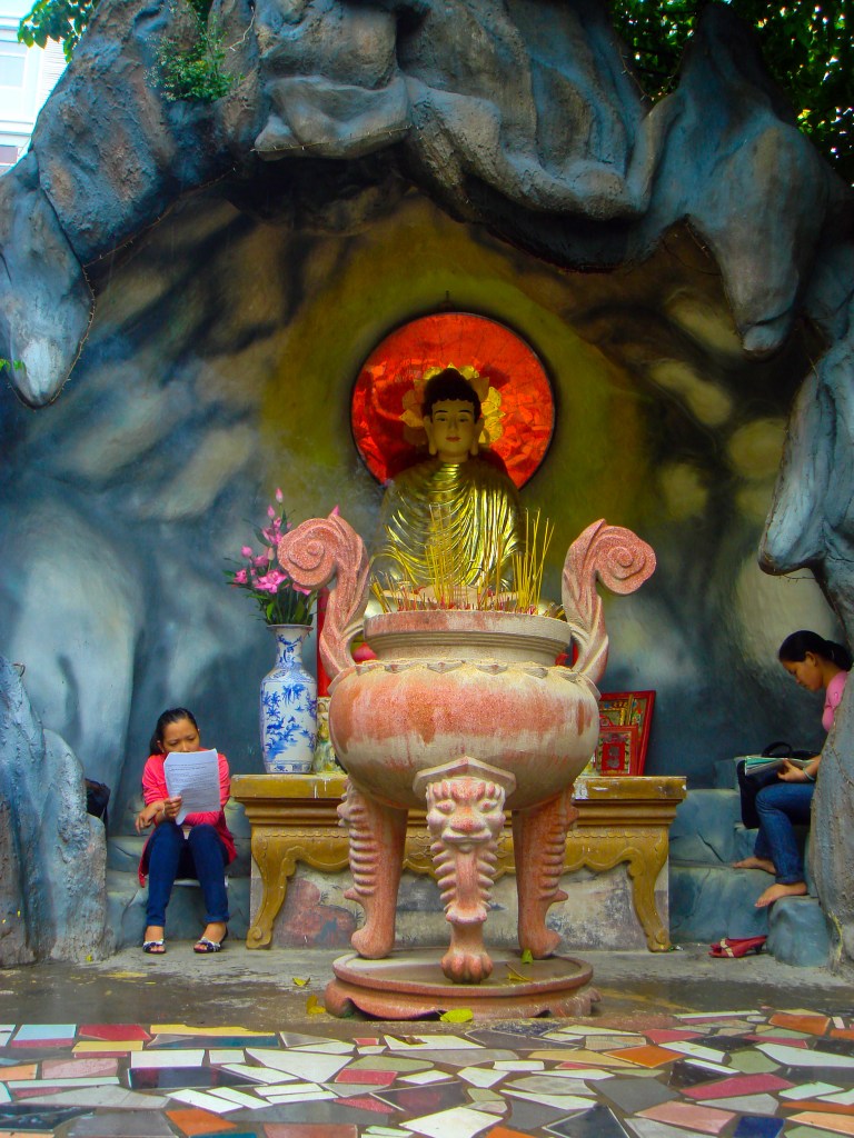 Two young women study next to a Buddhist statue