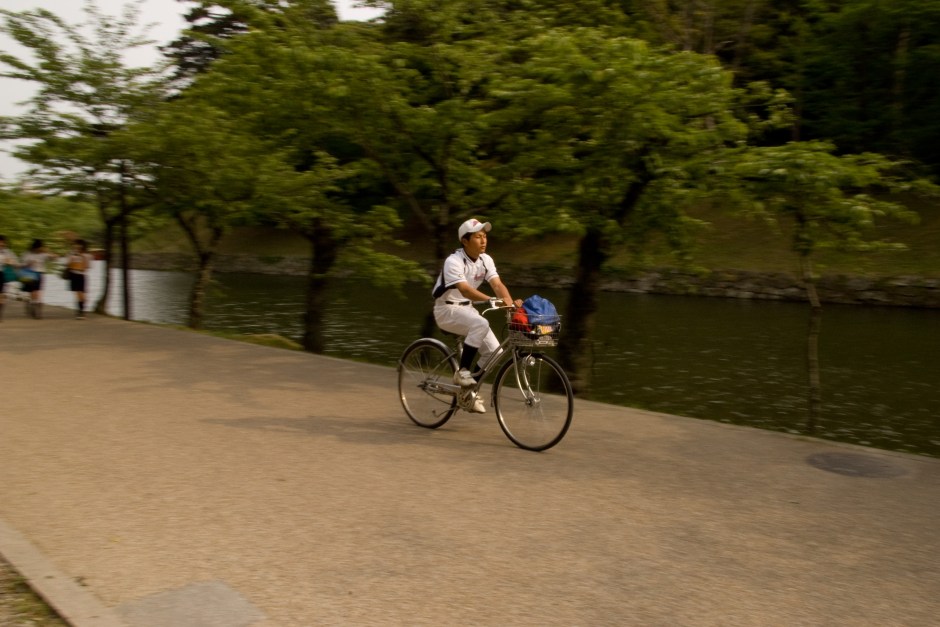 A boy rides his bike to baseball practice after school