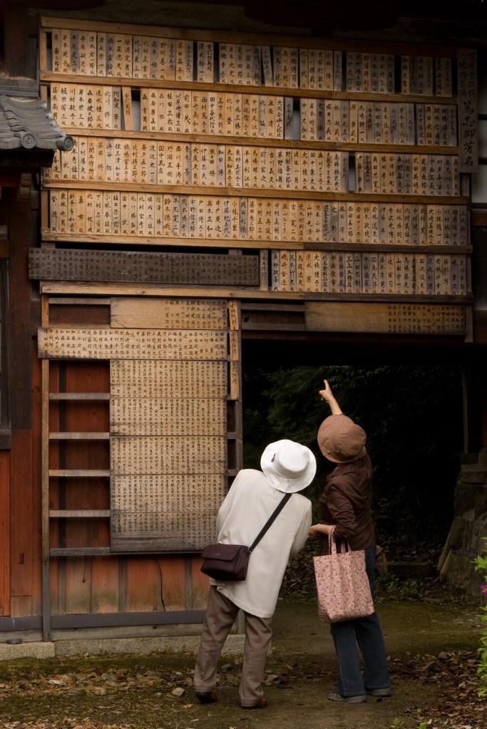 An elderly couple review prayer boards at a Shinto Shrine