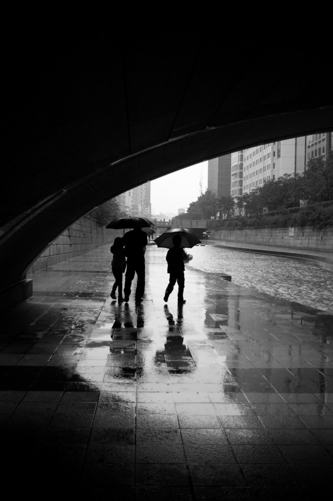A family strolls along a rainy stream