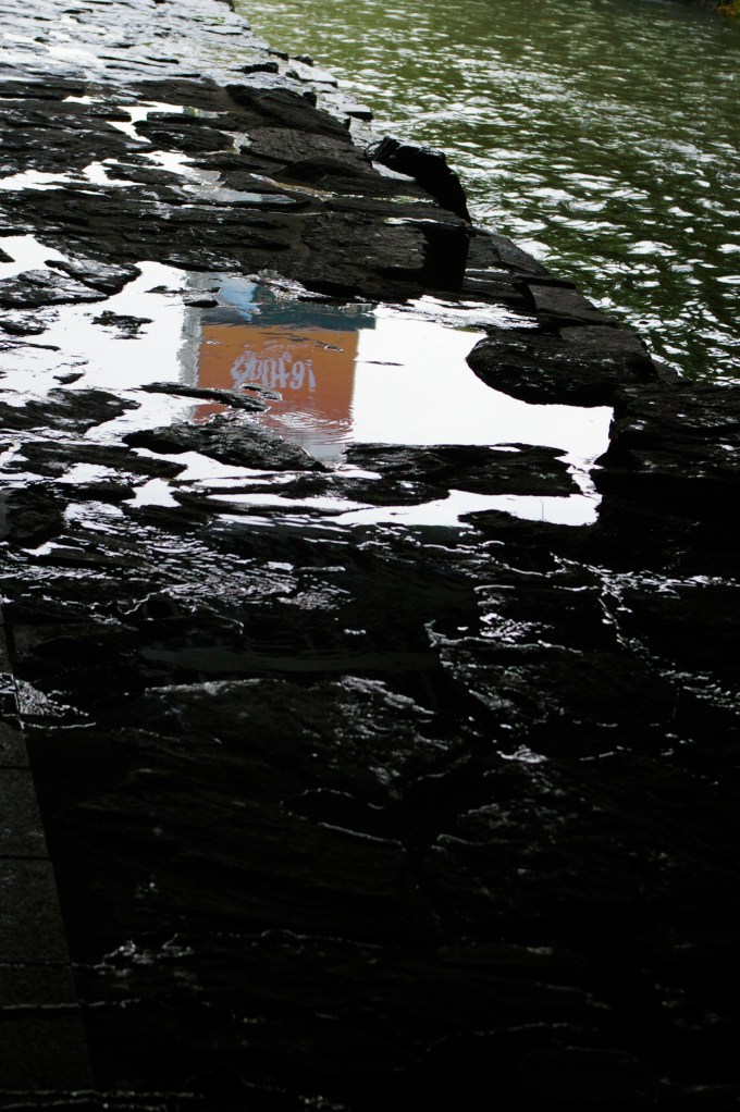 The popular shopping megaplex, Doota, is relfected in the stone walkway of the Cheonggyecheon