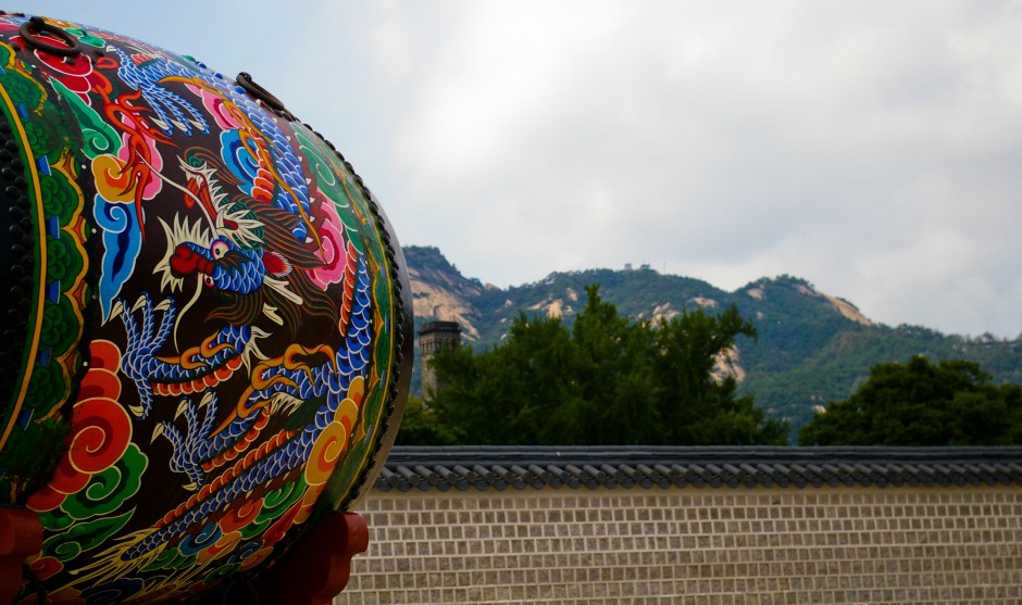 A traditional painted drum faces a nearby mountain range, Gyeongbokgung, Seoul