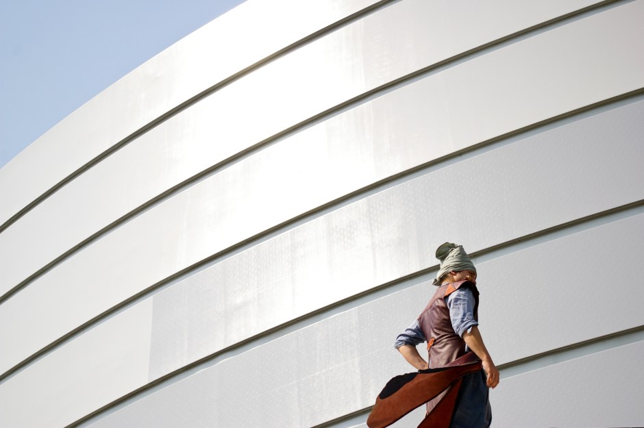 A man in historical Korean clothing stands next to the old City Hall building