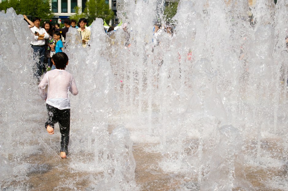 A young boy plays in the public fountain in Gwanghwamun, Seoul on a sultry day