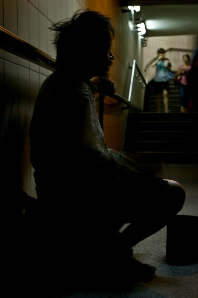 An elderly man plays for donations in a Beijing Subway station