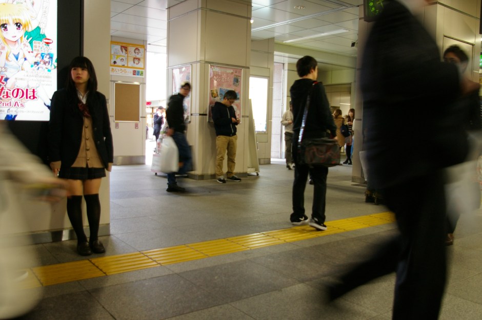 A young girl waiting amid the hustle of Akihabara Station