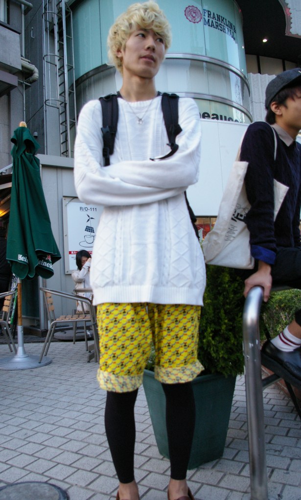 A young man waits for admirers on a corner in Harajuku