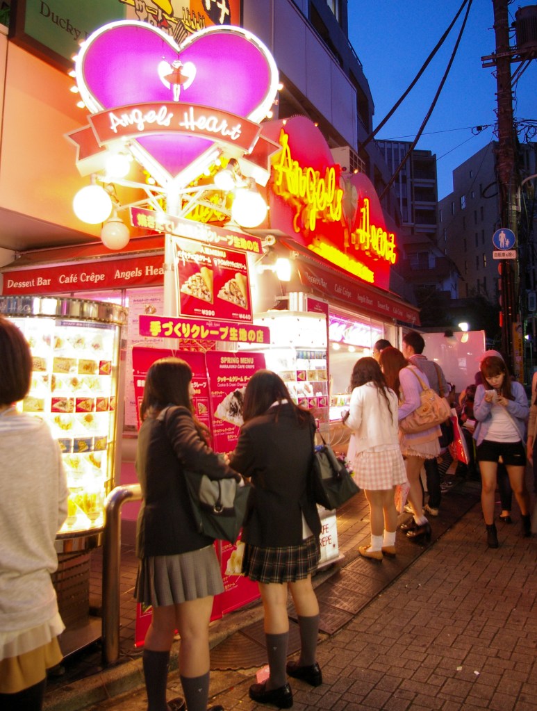 Young shoppers wait in line for waffles under the neon lights