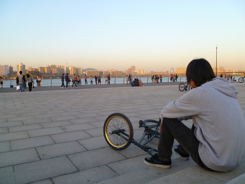 A trick cyclist relaxes at twilight on the Han River, Seoul